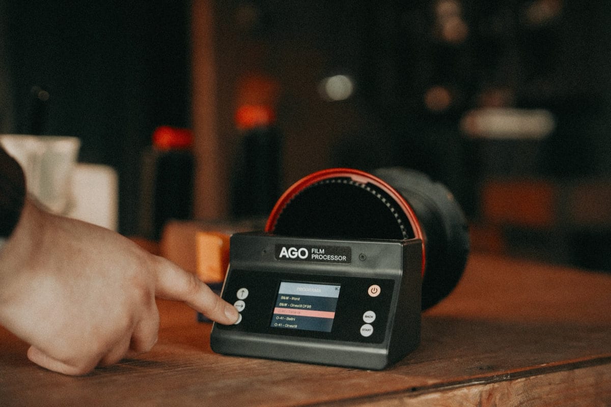 AGO フィルムプロセッサーの操作パネル。ディスプレイに現像プログラムの一覧が表示され、指がボタンを操作している